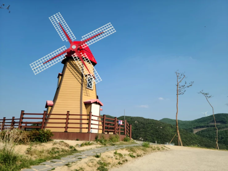 a brown and red windmill sitting next to a trail