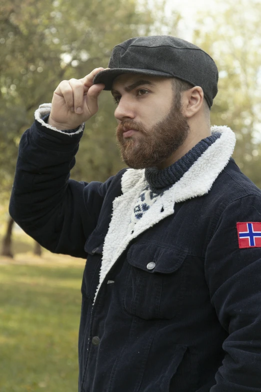 a young man with a beard and blue jacket looking at soing off camera