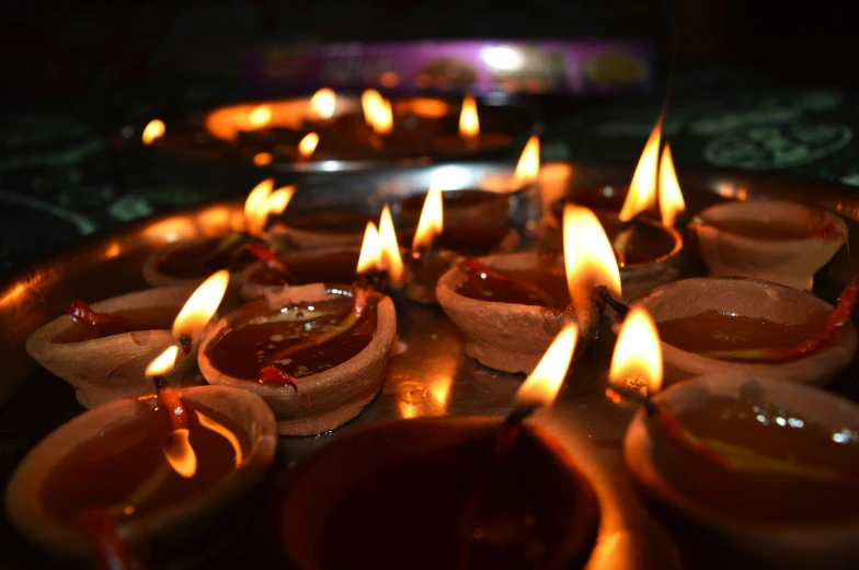 a large number of lit candles on a tray