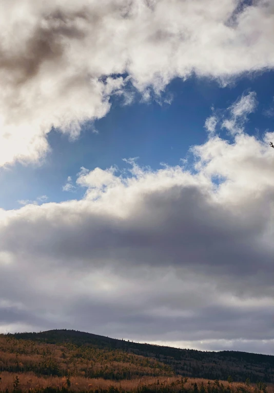 a plane flying in the air over the top of a hillside