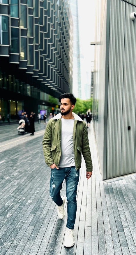 a man wearing jeans and an army jacket is walking down the street