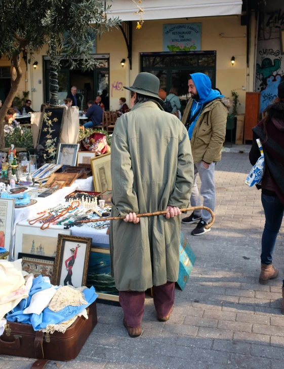 a man walking through an outdoor market carrying luggage