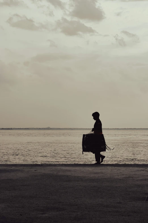 a man walking on the beach while holding soing in his hand