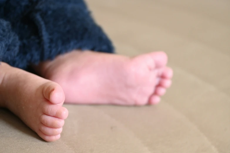 a foot laying down on a bed with sheets