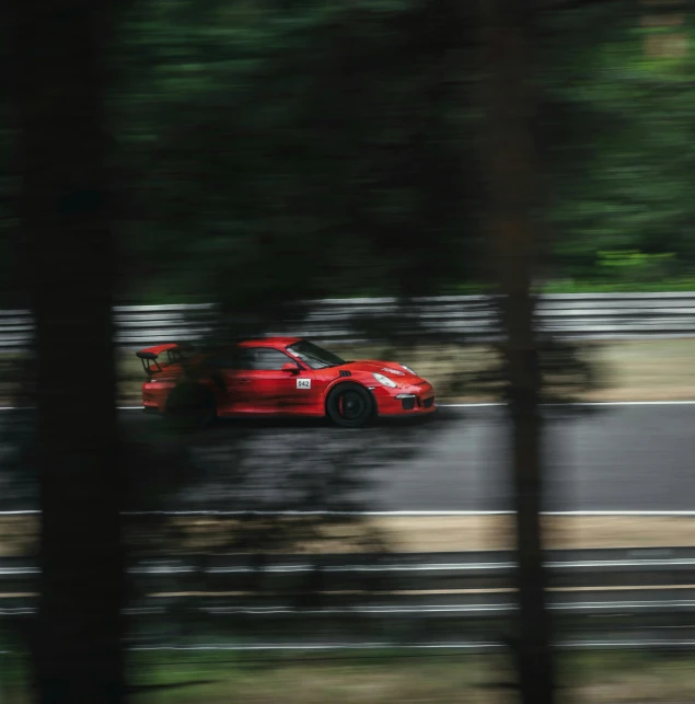 a red car is driving through the woods