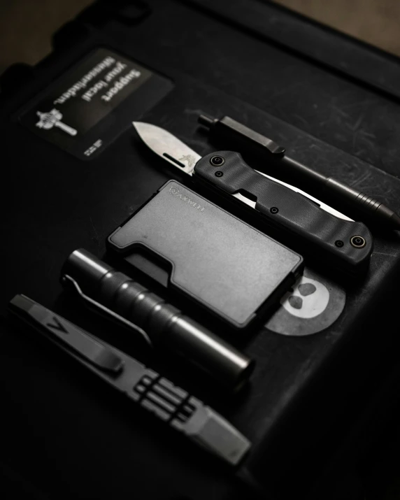 a black knife and some black tools sitting on top of a leather bag