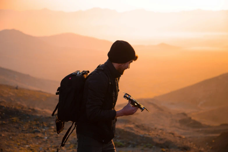 a person in a hat and jacket with a backpack looking at soing on the ground