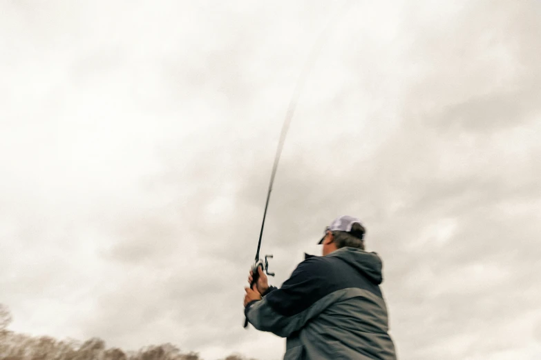 the man in gray jacket is holding a fishing pole