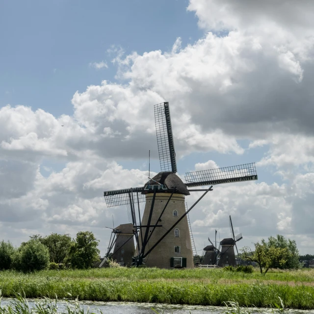 several windmills in a field near a stream