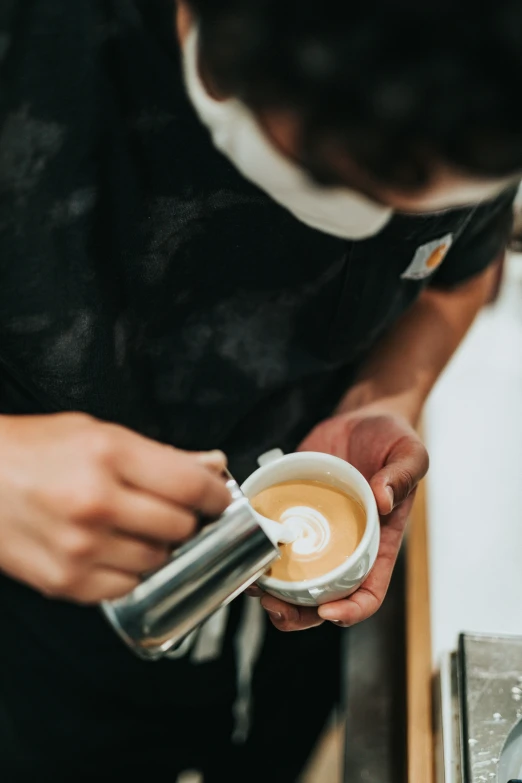 a person pouring coffee into a small cup
