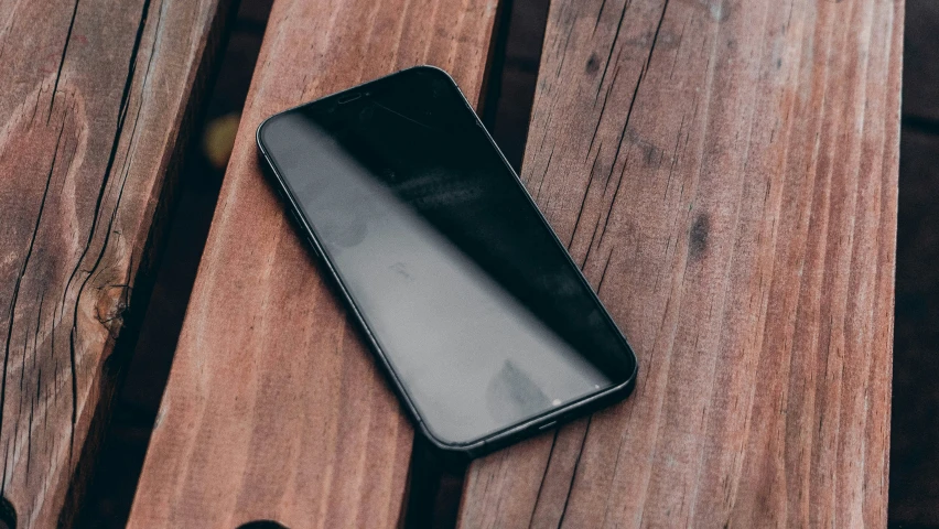 a cellphone with its case in a black design is sitting on the top of wooden table