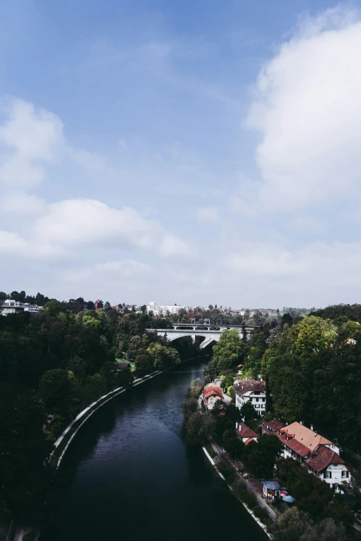 an aerial view of a river with homes, bridges and trees