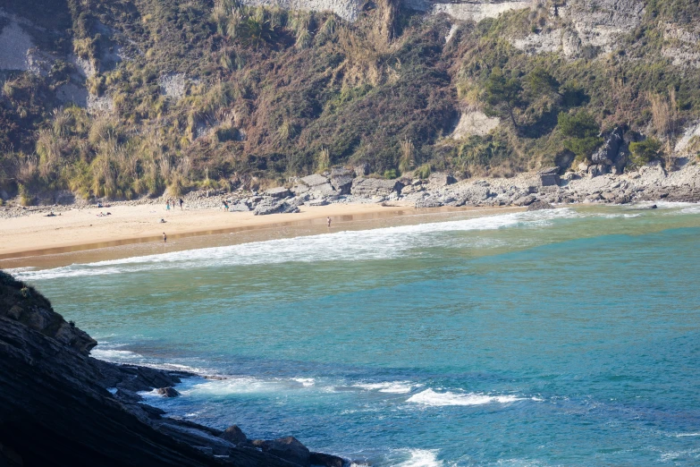 a beach with some people swimming in the ocean