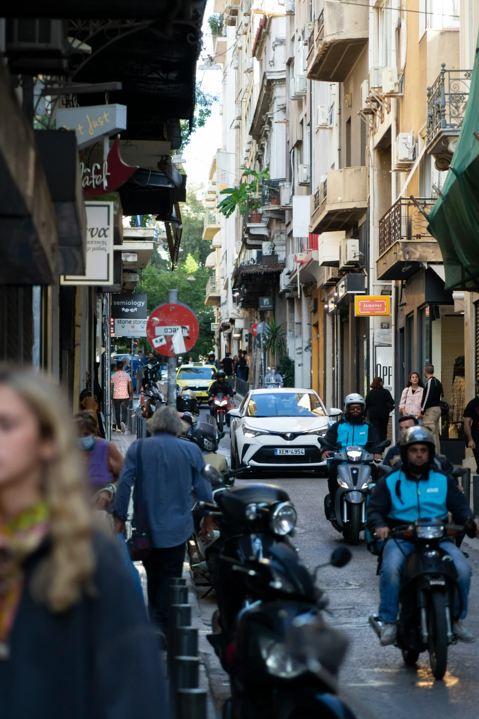 people ride motorcycles through a busy street lined with tall buildings