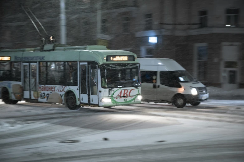 a white bus driving down a snow covered street