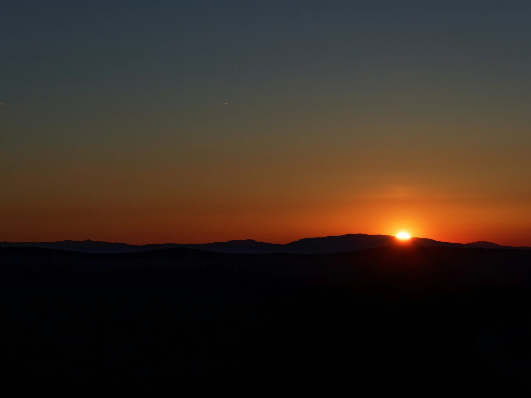 an airplane flying over a mountain during a sunset