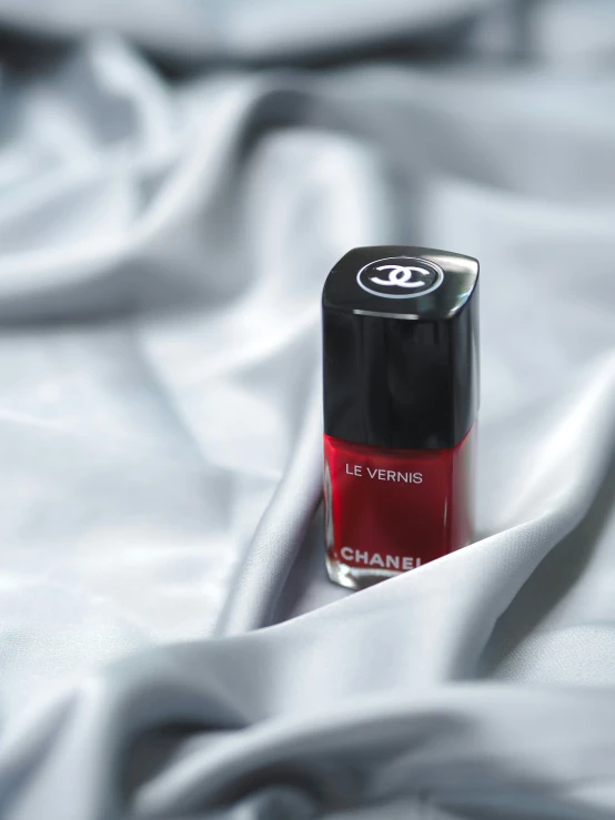 a red nail polish on top of a bed sheet