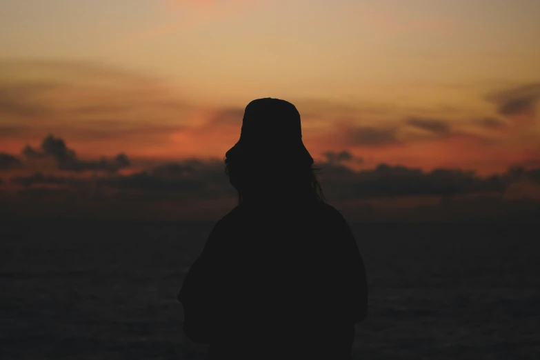 the person is silhouetted against an orange sky