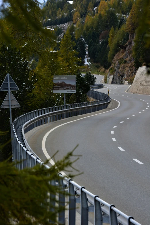 a street has a long curved curve and a hillside can be seen