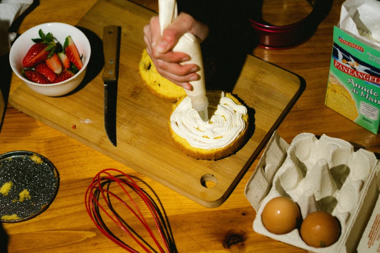 a woman spread out icing on a toast with strawberries