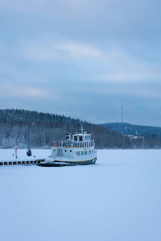 a boat in a frozen lake surrounded by trees
