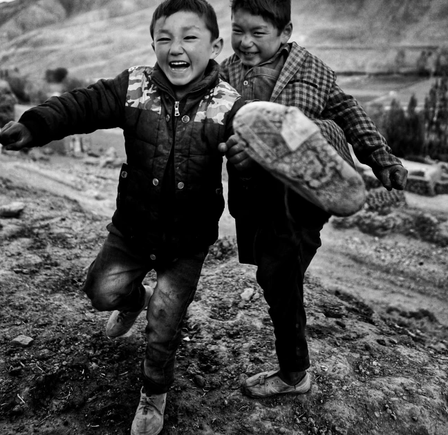 two children holding a baseball bat while running