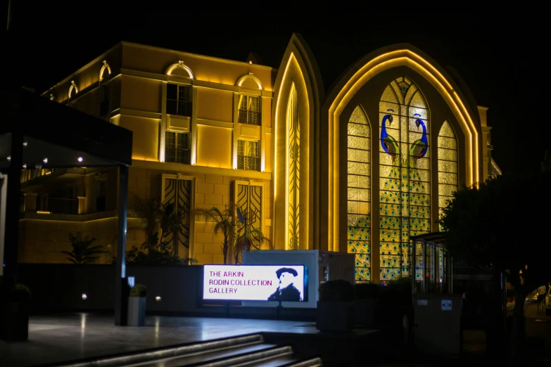 a lit up church with a large stained glass window