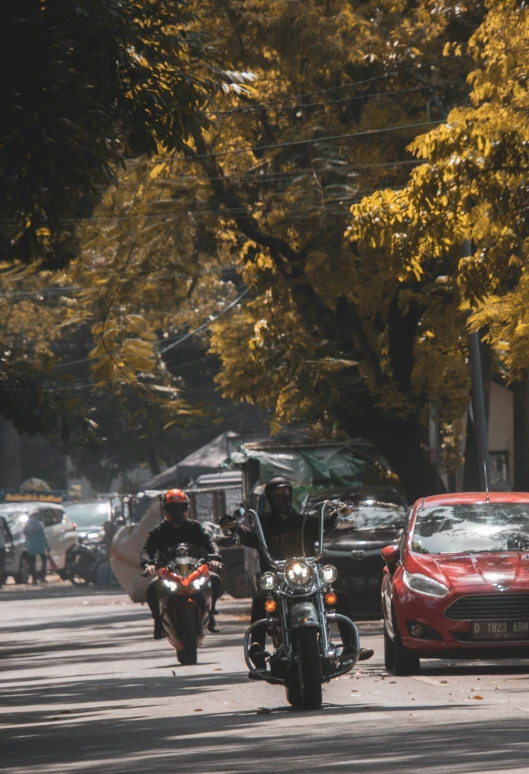 there is a man on a motorcycle next to a car and a red car