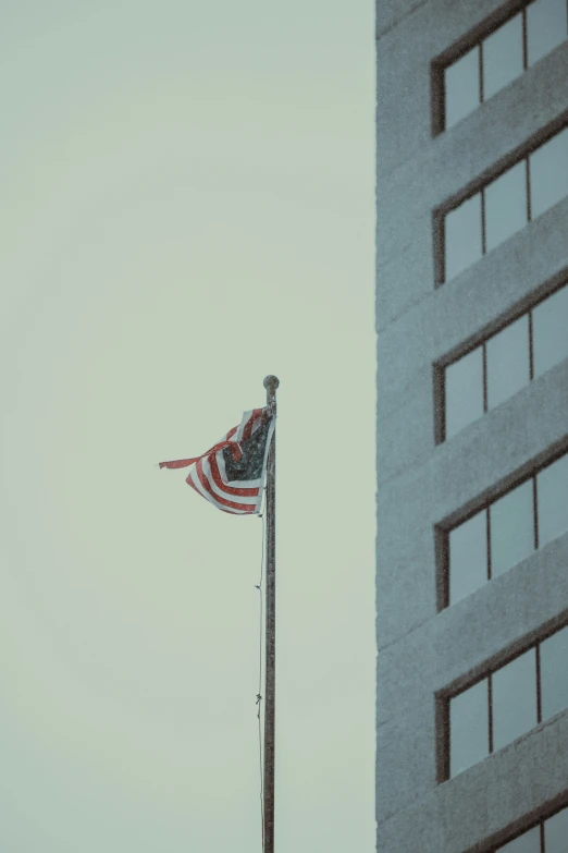 a tall american flag on a pole near a building