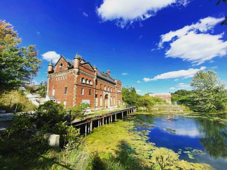 an old brick building on the side of a lake