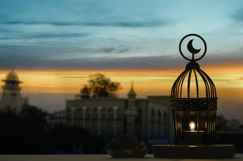 an old bird cage on the side of a building with the sun going down behind it