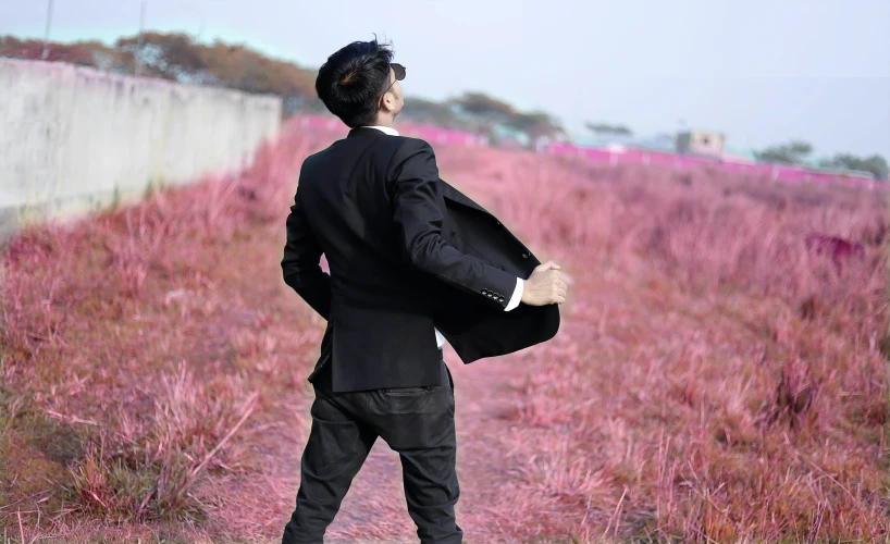 a man walking down a road past grass covered ground