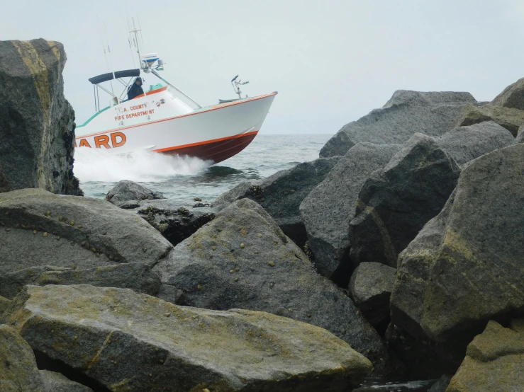 a boat is riding along on a rocky coast