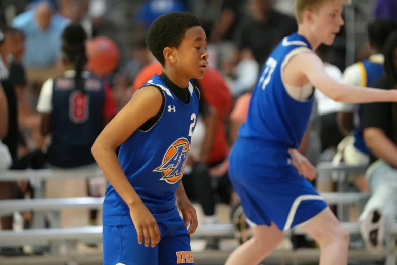 two boys wearing blue uniforms in the middle of a court