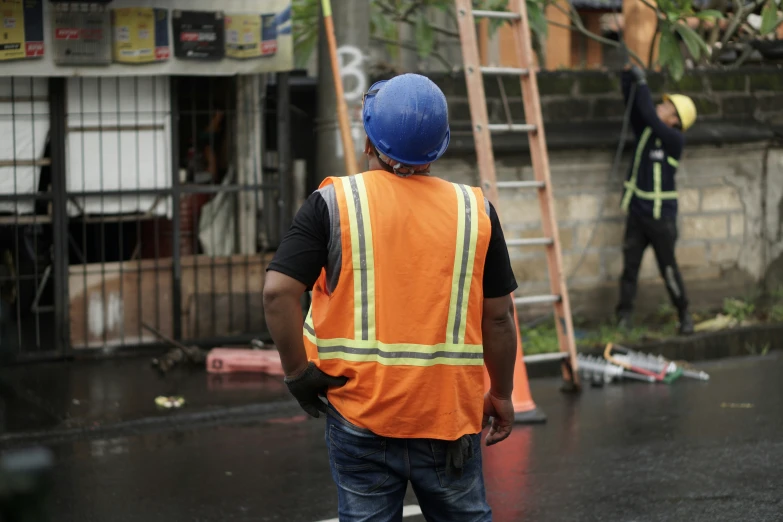 a man with a construction vest is standing next to a ladder and a ladder