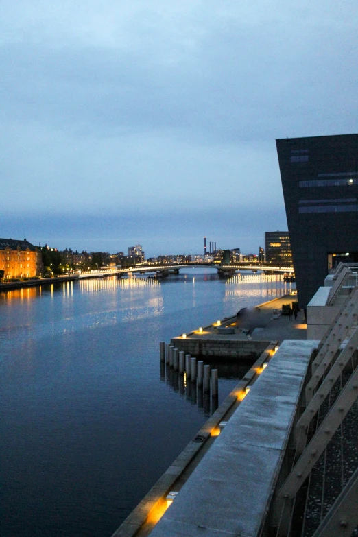 a dark body of water next to a long bridge