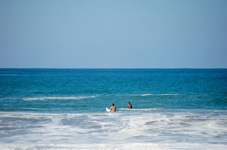 two people standing on a surfboard in the ocean