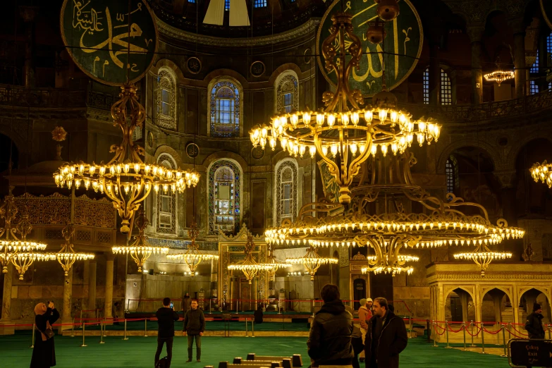 the large room has many chandeliers and big clocks on the walls