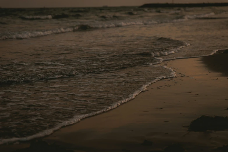 a wet ocean on a beach next to a rocky shore