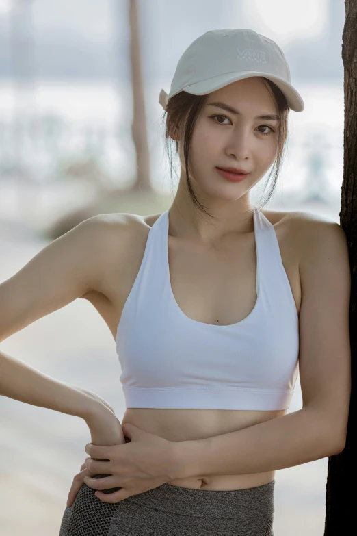 an asian girl wearing a sports  is leaning on a tree