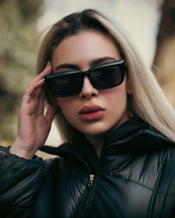 young woman with blonde hair wearing sunglasses and a black jacket