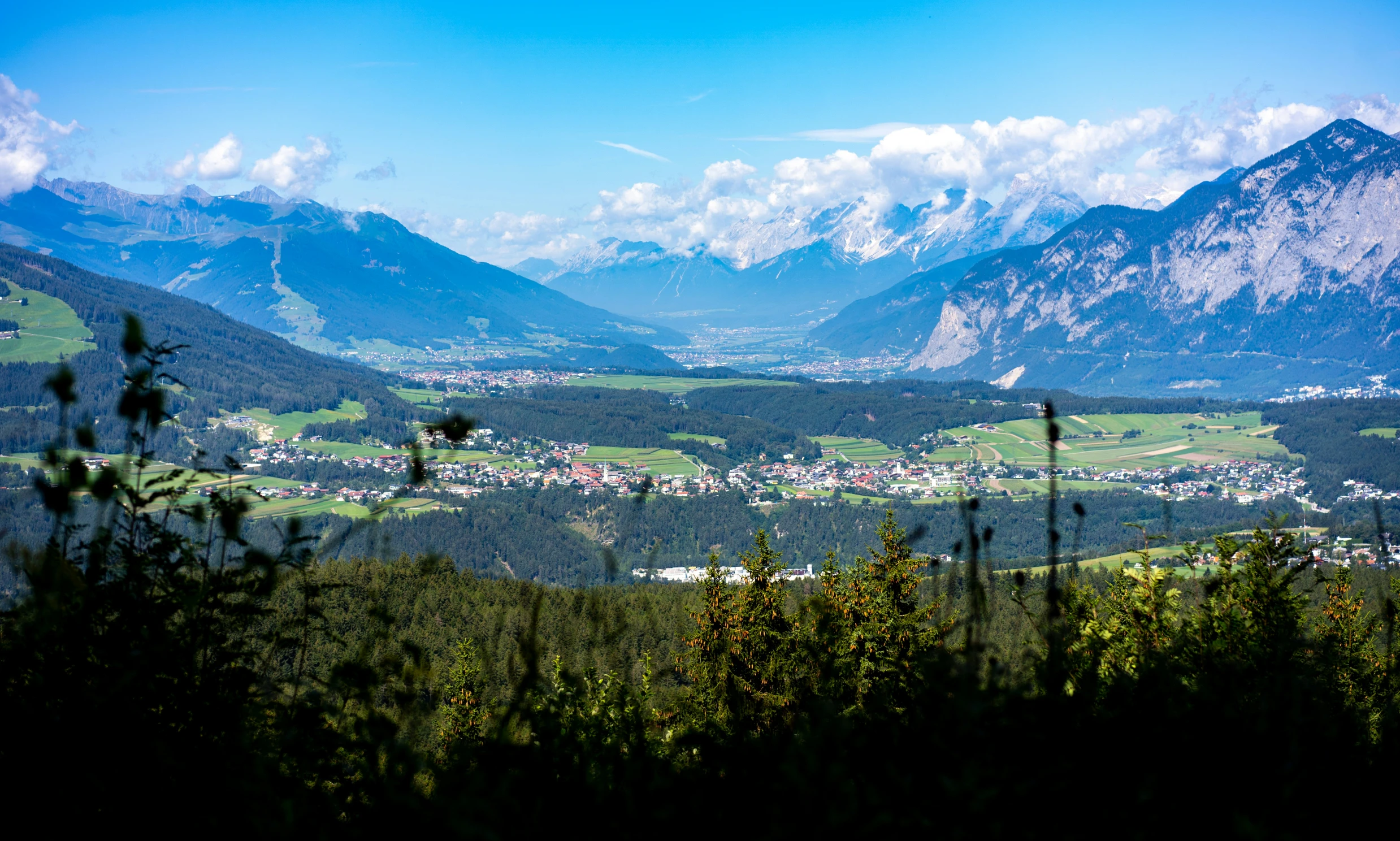 the mountains are behind this green valley