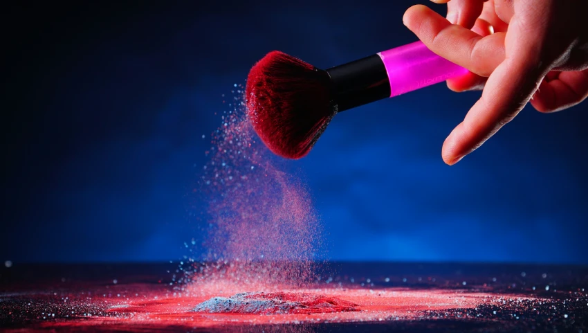 the person is holding a make - up brush and powder