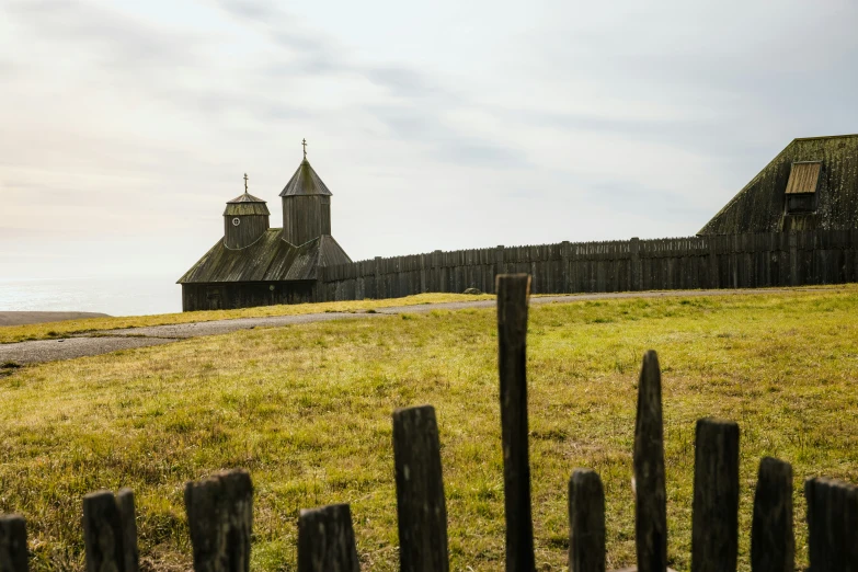 a grassy field in front of a house on the ocean