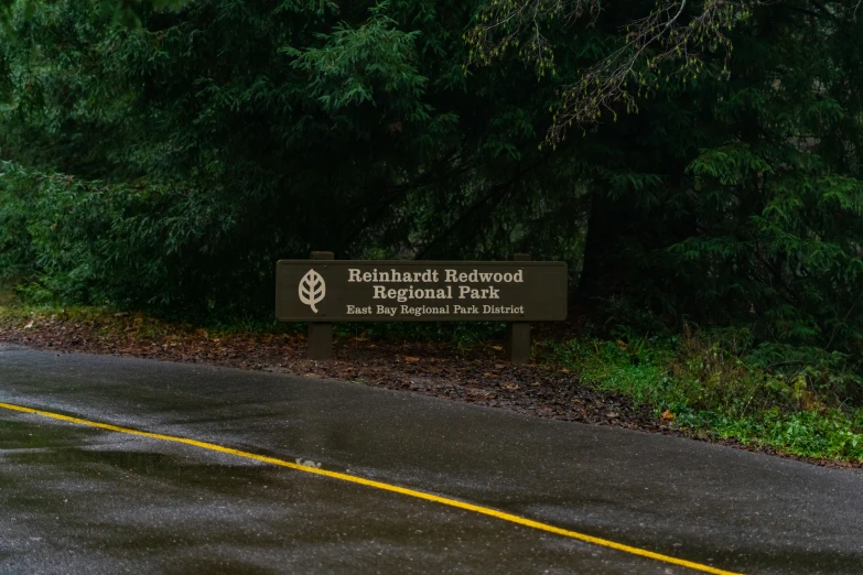 a sign on the side of a road near some trees