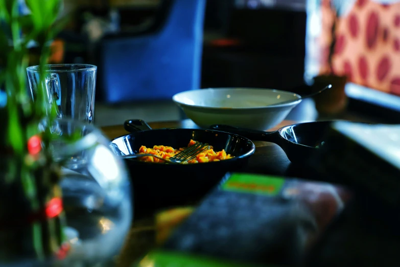 a table with a bowl and serving trays of food on it