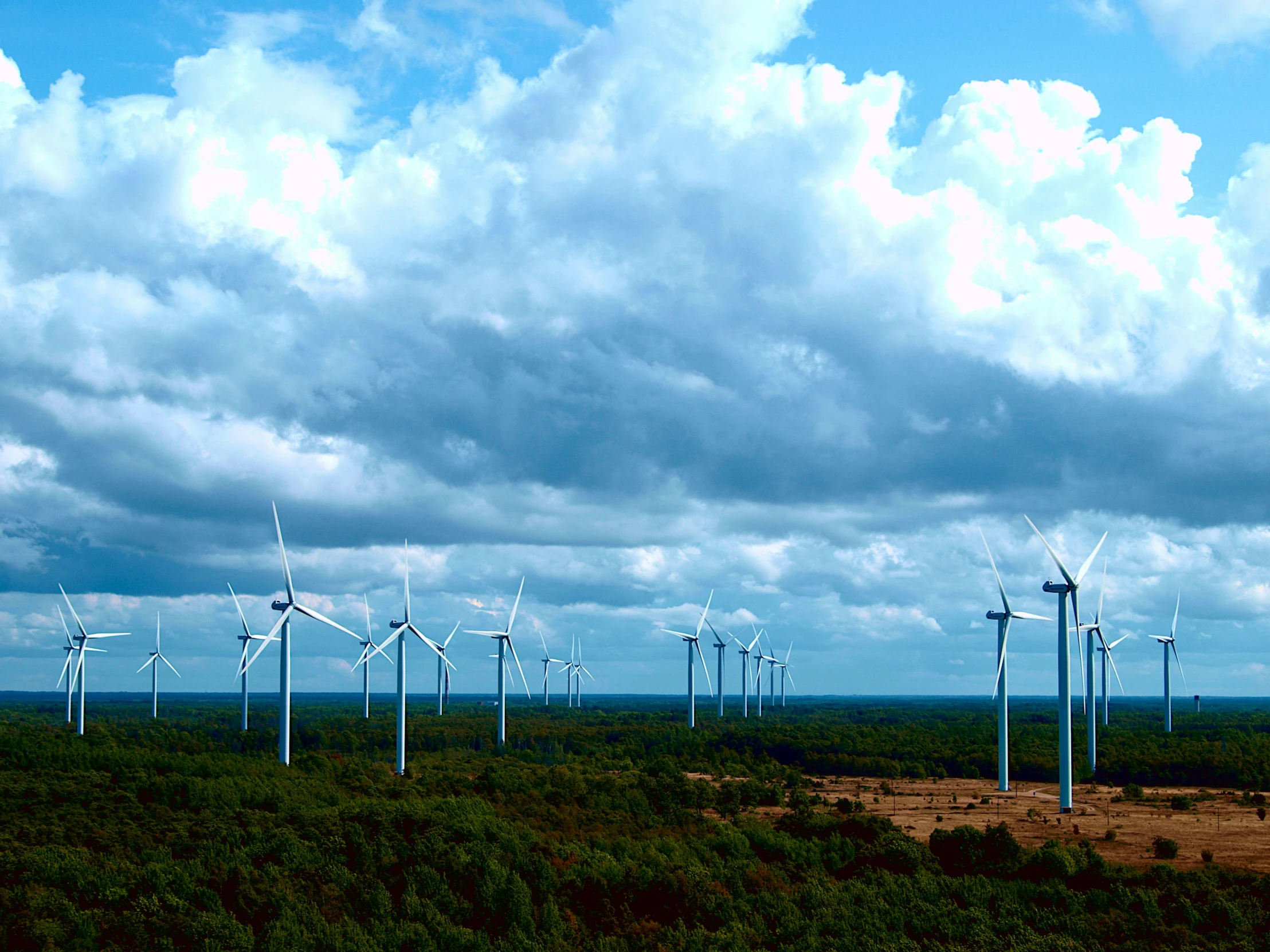 several wind turbines stand in the distance on a cloudy day