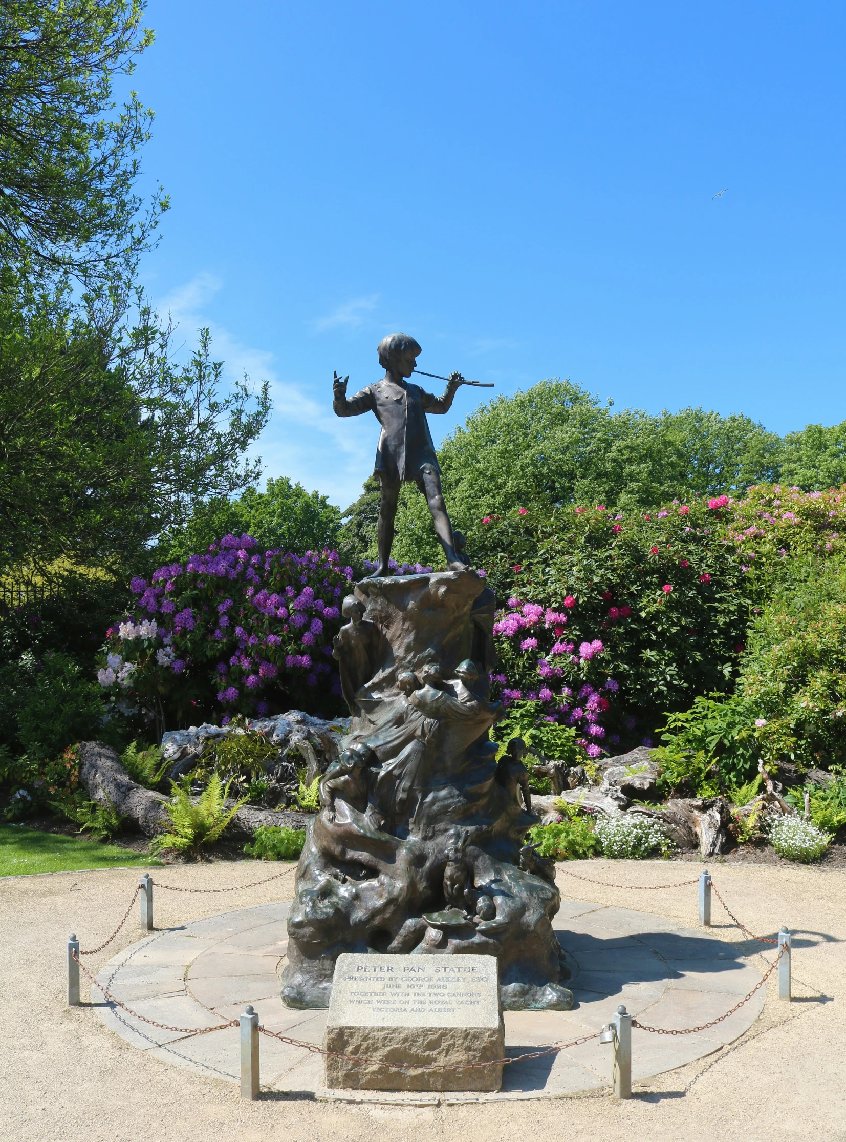 a statue of a boy standing on top of a rock with arms spread out