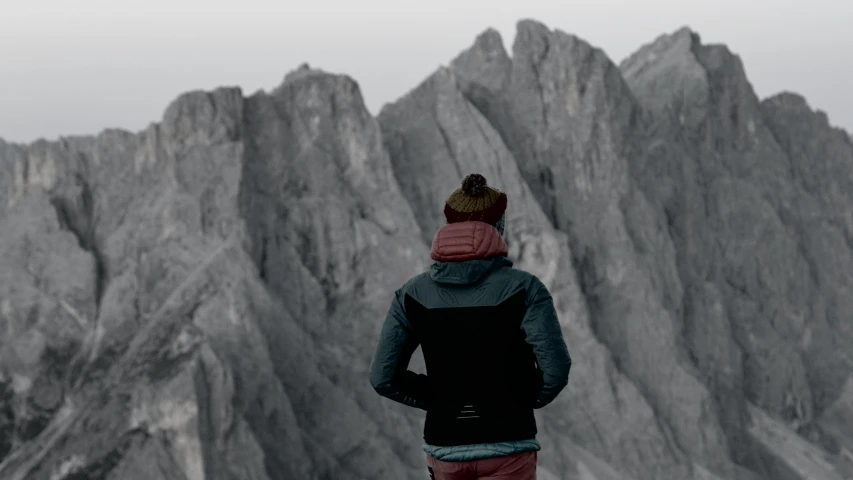 a man standing on top of a mountain next to a tall rock