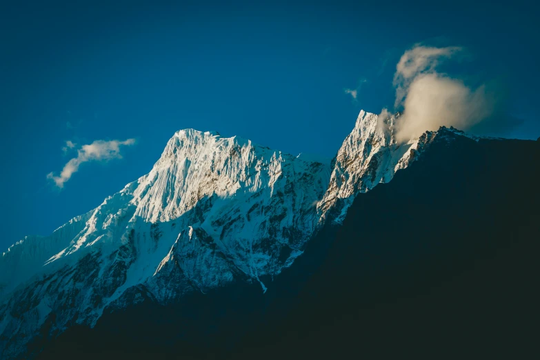 the top of the snowy mountains has some clouds